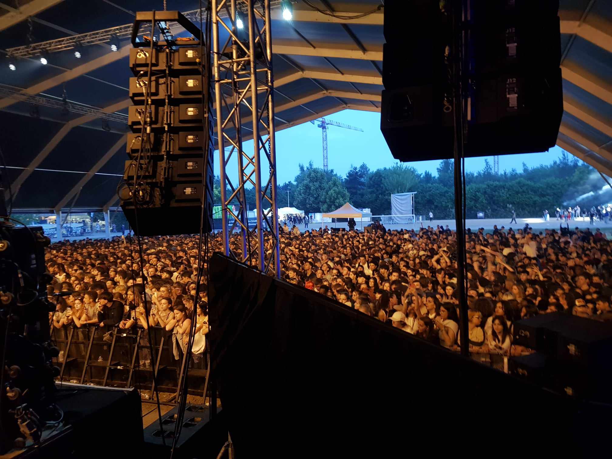 Vue depuis la scène : système son, structure et public sous un chapiteau de festival